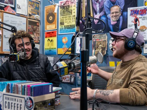 Students in front of microphones in a radio station.