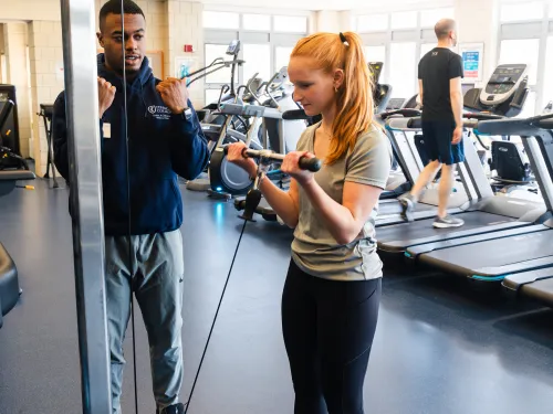 Fitness specialist assists member with their form.