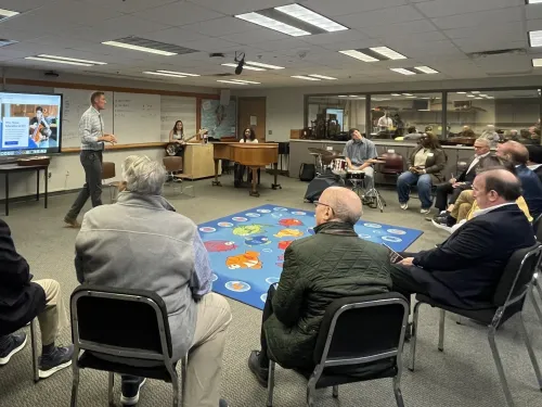 Man talks to people sitting in chairs in a circle.