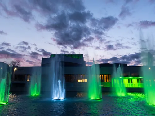 Ithaca College's iconic fountains, lit green at night.