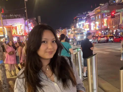 Student standing on sidewalk of busy city street