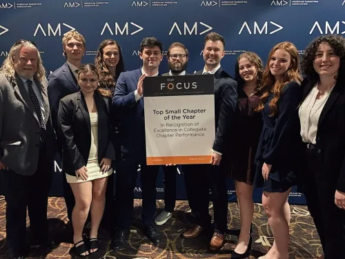 A group of students and their professor with a sign that says "Top Small Chapter of the Year"