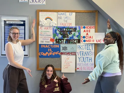 (Students pose with social change posters)