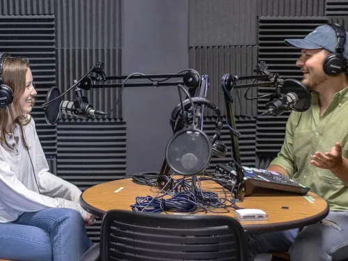 two students sit across from each other with a microphone in between them