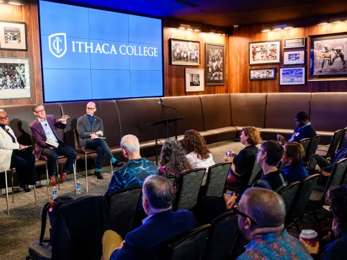 Three people sitting in chairs in front of an audience.