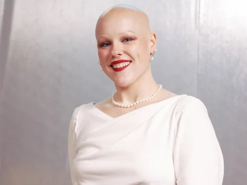 Woman wearing white dress and pearls.