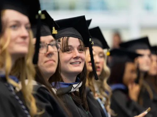 Graduate students at commencement wear caps and gowns.