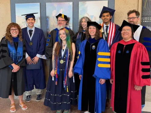 Physics graduates and faculty stand outside CNS 206/208