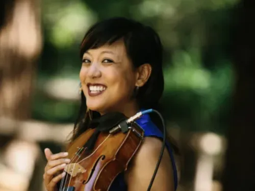 Bora Yoon smiling and holding a violin