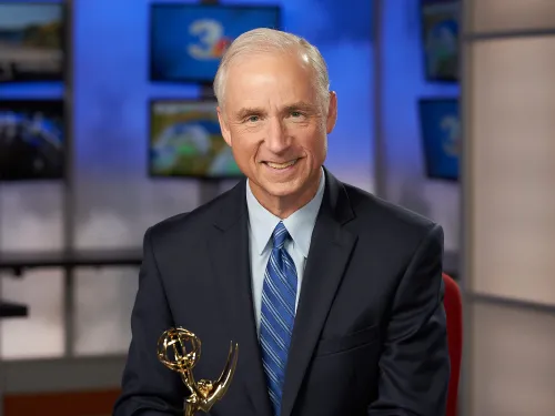 A man in a suit with an Emmy Award.