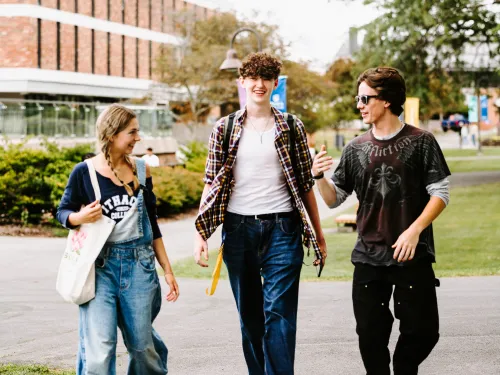 Three students walking on academic quad.
