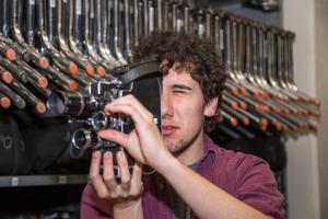 Tyler Macri looks into camera while adjusting lens