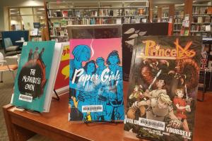 three graphic novels on display on a shelf