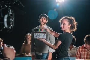 A student holds a film clapperboard in front of an actor prior to a scene. 