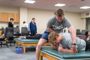 Student performing physical therapy on a client in a clinical classroom.