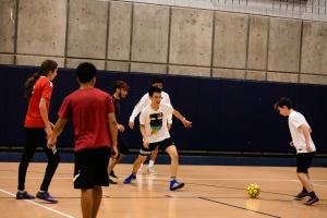 A group of students playing soccer indoors.