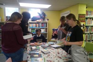 Students look at graphic novels with librarian 