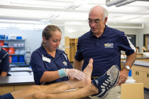 A faculty member provides oversight to a student assessing an ankle injury.