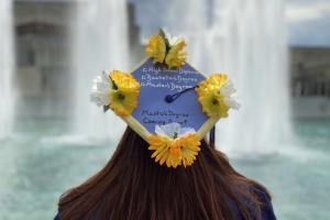 college graduate facing away toward fountain