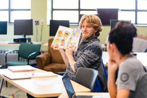 A male student holds up a children's book as part of a class discussion