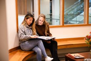 Two students sitting together and reviewing paperwork