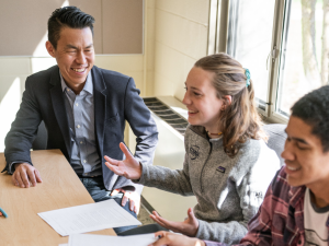 Associate professor Jack Wang laughing with two students in class.