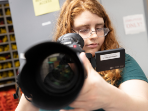 Student holds camera while adjusting the lens. 