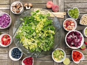 bowl of green salad surrounded by fruit