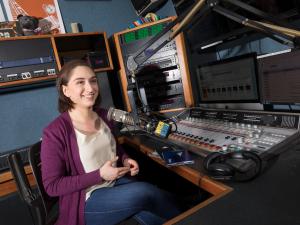 Student behind microphone in radio studio.