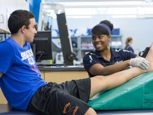 student athletic trainer helping athlete