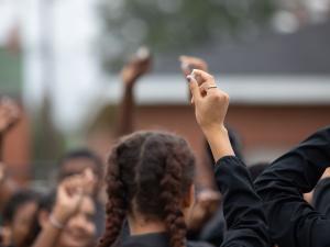 A graphic design. MLK Scholars holding up small pebbles with an MLK Scholar logo overlay
