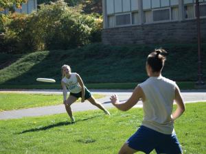 Two students playing frisbee outdoors.