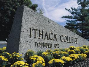 stone entrance to ithaca college with flowers on a sunny day