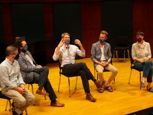 Five members of the faculty sitting in chairs on a stage.