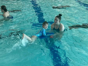 A child swimming in the water with a student-athlete