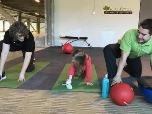 two adults and a child stretching on yoga mats