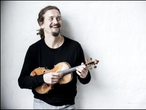 a man holds a violin and smiles