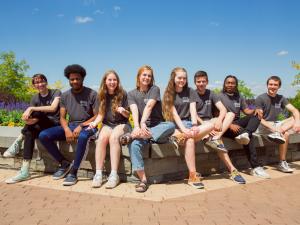 A group of students sitting on a stone bench at Ithaca College