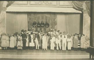 Black-and-white photo of actors on stage, in costume.
