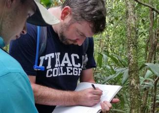 A man writing notes in the jungle