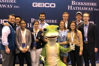 A group of people posing with the Geico gecko