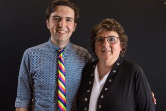 A young Caucasian man in a rainbow-colored tie poses with his mother.