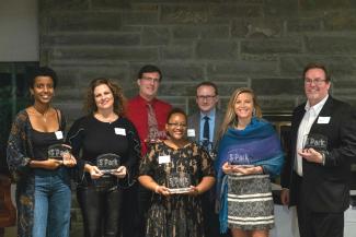 A group of men and women holding glass awards