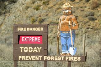 A sign with "Smokey the Bear" warning about the extreme risk of forest fire