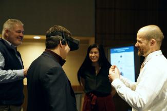 A man wearing VR goggles stands with three other people