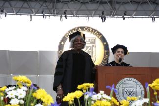Two women on stage wearing academic regalia