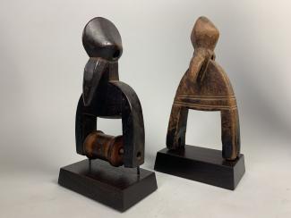 Two carved wooden pulleys set on display pedestals.