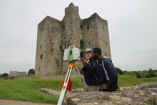 Two men use a 3D scanner outside of a castle