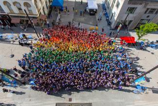 People wearing colored shirts to form a rainbow