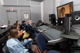 man in front of an audio mixing board teaches students